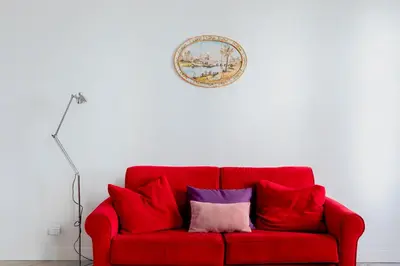 a red couch with two pillows on a white wall at Domus Degli Angeli in Rome