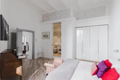 a white bedroom with a large bed and a living room at Domus Degli Angeli in Rome