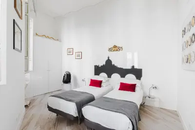 two beds in a room with white walls and red pillows at Domus Degli Angeli in Rome