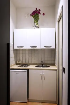 a kitchen with white cabinets and a sink and a vase of flowers at Trasteverome45 in Rome