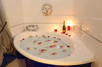 a bath tub with a bottle of wine and a candle at Grand Tour Rome Suites - Liberty Collection in Rome
