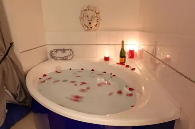 a bath tub with a bottle of wine and a candle at Grand Tour Rome Suites - Liberty Collection in Rome