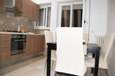 a kitchen with a black table and white chairs at Vatican In The Moonlight Apartment in Rome