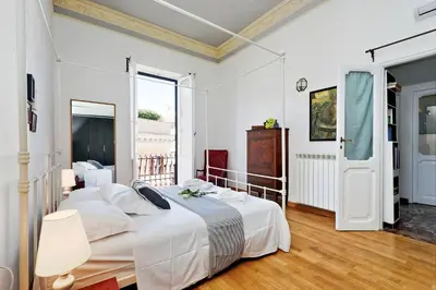 a white bedroom with two beds and a large window at Spagna Penthouse in Rome