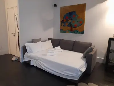 a bed with white sheets and a couch in a room at Vatican Modern Apartment in Rome