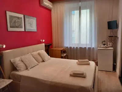 a bedroom with a white bed and a red wall at B&B Vaticanrooms in Rome