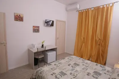 a bedroom with a bed and a desk and a curtain at Rooms Monteverde in Rome