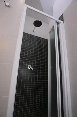 a shower with a black tile floor and a shower head at Rooms Monteverde in Rome