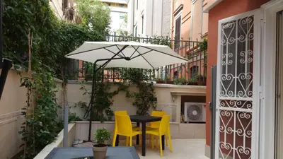 a black table with yellow chairs and an umbrella at La Casetta di Ely in Rome