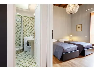a bedroom with two beds and a bathroom with a sink at Apartment Via Giulia in Rome
