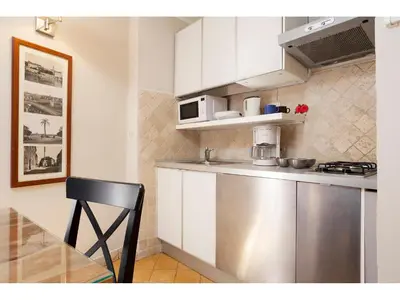 a kitchen with white cabinets and a black chair at Apartment Via Giulia in Rome
