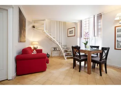 a living room with a red chair a table and a staircase at Apartment Via Giulia in Rome