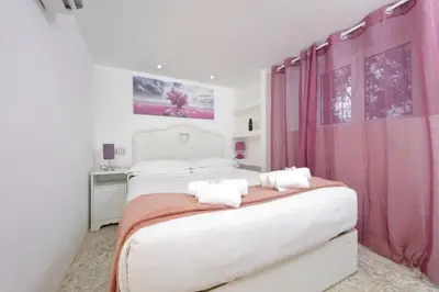 a white bedroom with pink curtains and a bed at 4BNB - Domus Colosseo in Rome
