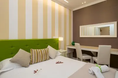 a bedroom with a bed with a green headboard and a desk at Zefiro Home in Rome