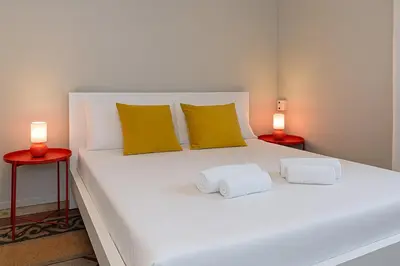a white bed with two lamps on two tables at èROMA - ESQUILINO Apartment in Rome