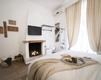 a white bedroom with a fireplace and a bed at Maison Coquette in Rome
