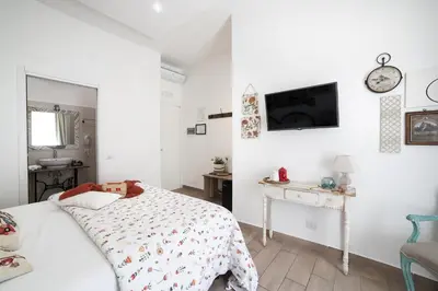 a white bedroom with a bed and a desk at Maison Coquette in Rome