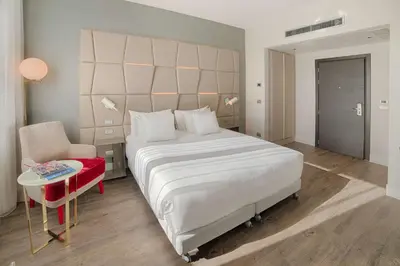 a bedroom with a large white bed and a chair at NH Collection Palazzo Cinquecento in Rome