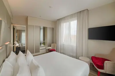 a hotel room with a large white bed and a tv at NH Collection Palazzo Cinquecento in Rome