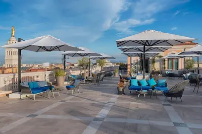 a patio with blue chairs and umbrellas on a roof at NH Collection Palazzo Cinquecento in Rome