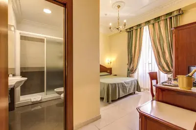 a bathroom with a bedroom with a bed and a mirror at Hotel Contilia in Rome