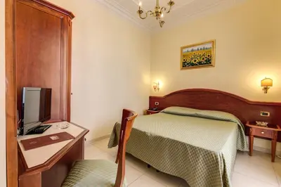 a bedroom with a bed and a desk and a tv at Hotel Contilia in Rome