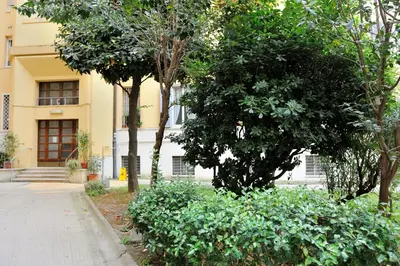 a building with trees in front of a sidewalk at Alexia Home in Rome