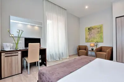 a bedroom with a large bed and a desk and chairs at Relais Servio Tullio in Rome