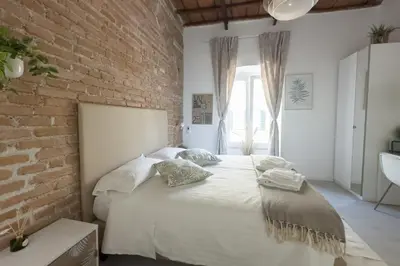 a bedroom with a white bed with a brick wall at White Ostilia Guesthouse in Rome