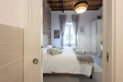 a bedroom with a bed with white sheets and pillows at White Ostilia Guesthouse in Rome