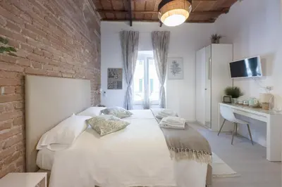 a bedroom with a white bed and a brick wall at White Ostilia Guesthouse in Rome