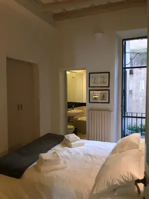a bedroom with a bed with white sheets and a window at La Casa In Vetrina in Rome
