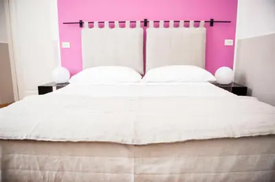 a bedroom with a large bed with a pink wall at Florian Rooms Guest House in Rome