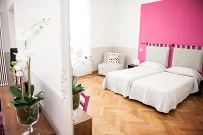a bedroom with two beds and a pink wall at Florian Rooms Guest House in Rome