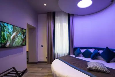 a purple bedroom with a bed with blue pillows at Colonna Suite Del Corso in Rome