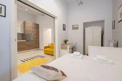 a bedroom with a white bed and a yellow couch at A 20 Gradini dai Musei Vaticani in Rome