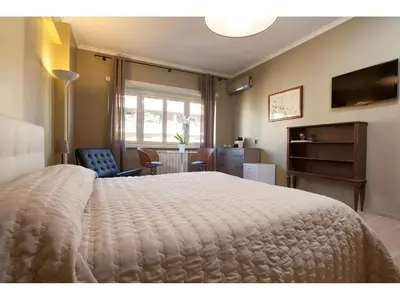 a bedroom with a large white bed and a desk at Alex's Guest House in Rome