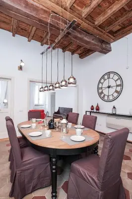 a dining room with a table and chairs and a clock at Trastevere Wonderful 3BR Apartment in Rome