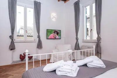 a bedroom with a bed and a chair and windows at Trastevere Wonderful 3BR Apartment in Rome
