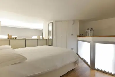 a white bedroom with a large bed and a kitchen at St. Peter Loft in Rome