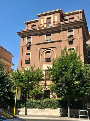a tall pink building with trees in front of it at The Queen in Rome