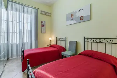 a bedroom with two red beds and a chair at Domus Eugenia in Rome