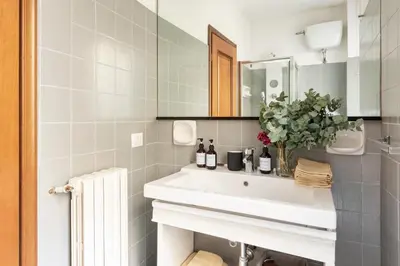 a white bathroom with a sink and a mirror at Annemary Maison in Rome