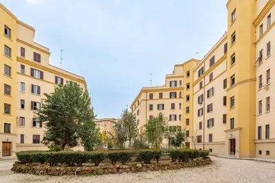 a row of yellow buildings with trees in a courtyard at Residenza Pasolini in Rome