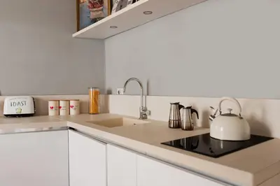 a white kitchen with a sink and a tea kettle at Campo de Fiori Bright Loft in Rome