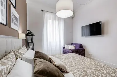a bedroom with a bed and a tv and a chair at BDC - The Choice, your 2-Bdr apt in Vatican district in Rome