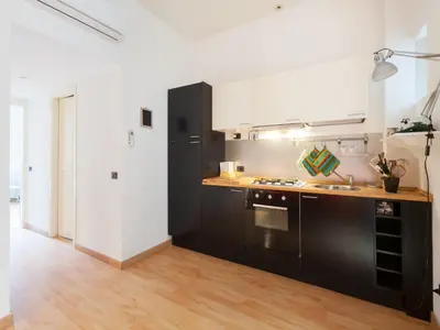 a kitchen with black and white appliances and wooden floors at Sabelli Nightlife Apartment-LA SAPIENZA-TERMINI STATION in Rome