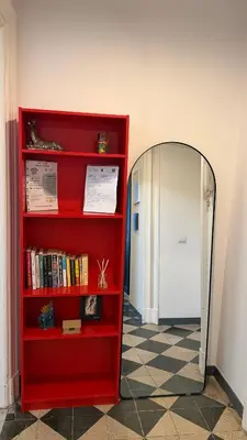 a red book shelf and a mirror in a room at St. John Apartment in Rome