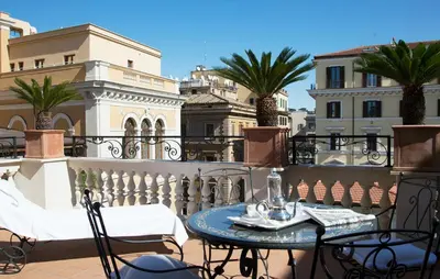 a table and chairs on a balcony with palm trees at Palazzo Dama - Hotel & SPA - Preferred Hotels & Resorts in Rome
