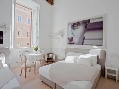 a white bedroom with a large bed and a table at Primo Piano Suites in Rome